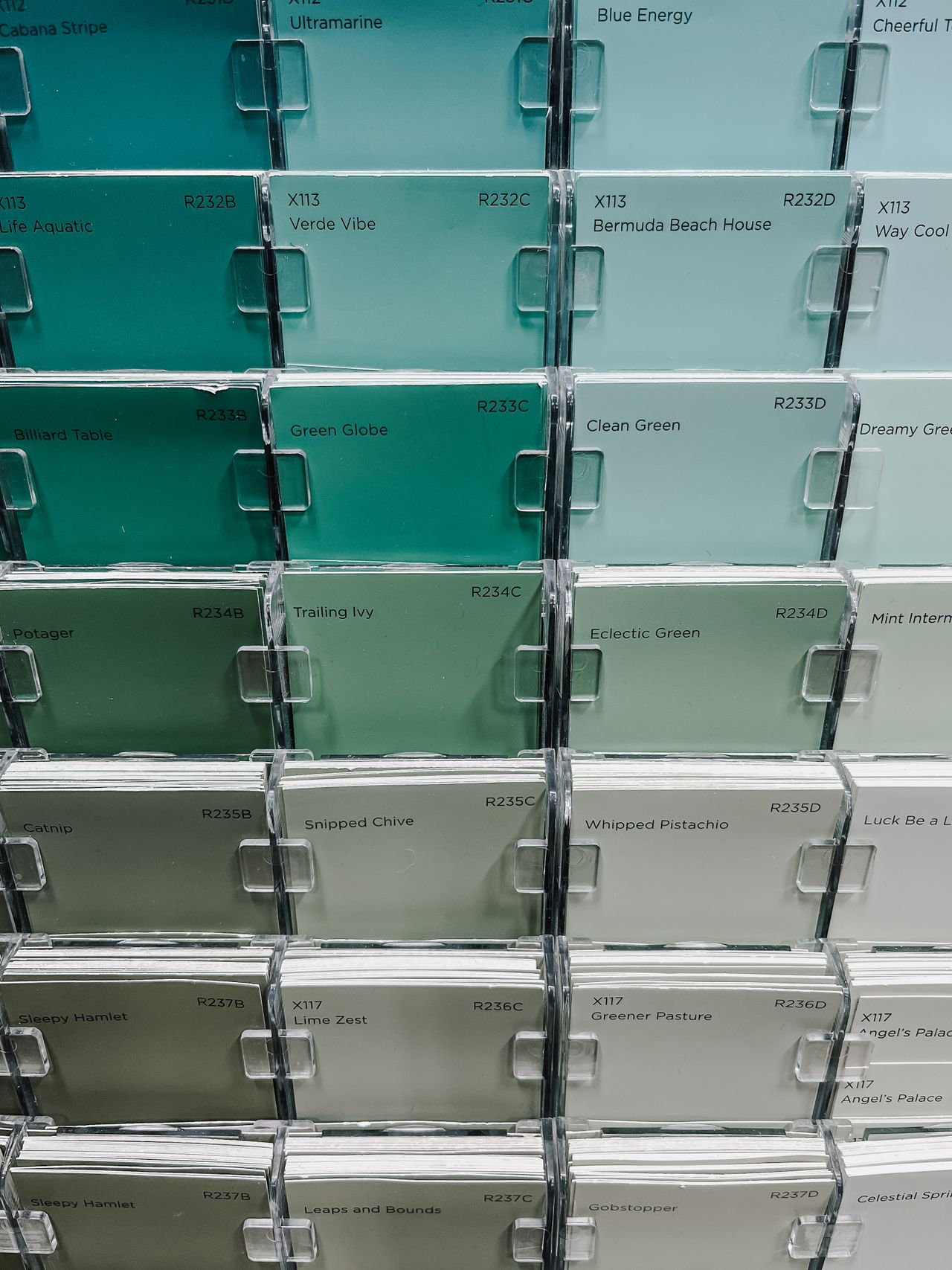 Wall of paint chip cards in a retail display, graduating from teal through sage to pale green