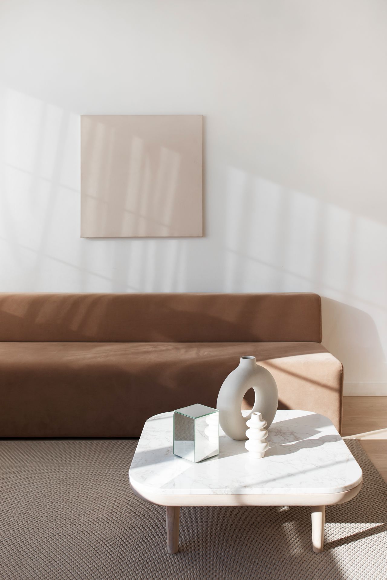Warm minimalist living room with a brown sofa and a marble coffee table
